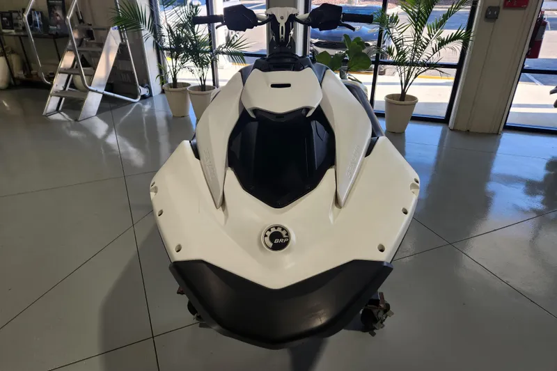 Slide: The Image of 2024 Sea-Doo Spark Trixx on trailer in showroom, surrounded by boats and plants. - 2