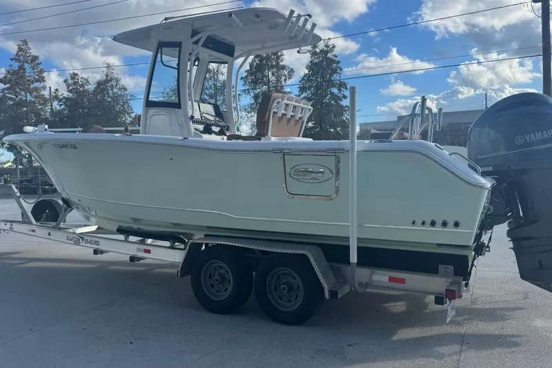 Slide: The Image of 2022 Sea Hunt Gamefish 25 boat on trailer, side view, under blue sky. - 5