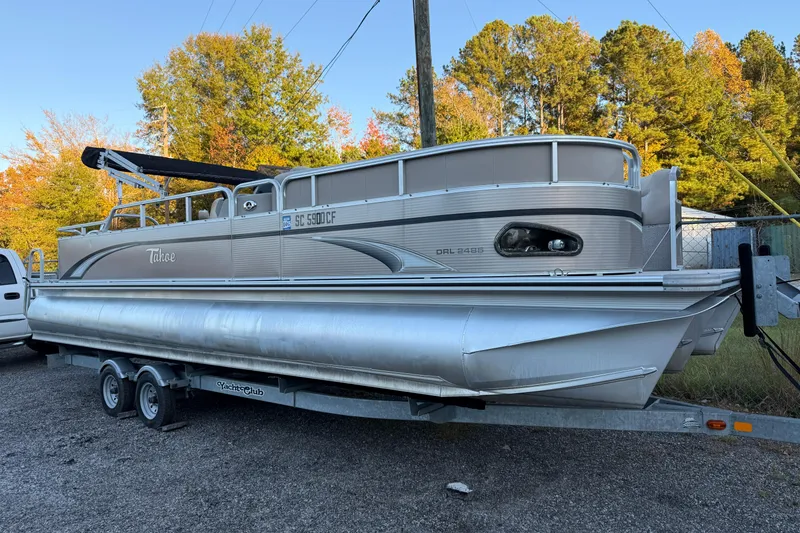 The Image of 2011 Tahoe Pontoon 2485 DRL on trailer, parked outdoors with autumn trees. - 0