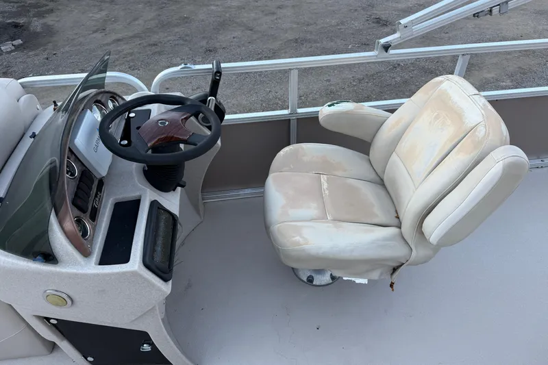 Slide: The Image of Steering console and seat of 2011 Tahoe Pontoon 2485 DRL boat, showing wear. - 4