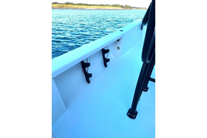 Slide: The Image of 2015 BlackJack 224 boat interior with rod holders, near calm blue water. - 14