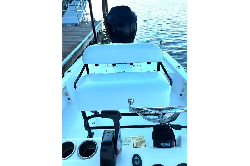Slide: The Image of 2015 BlackJack 224 boat interior with steering wheel and seating, docked by the water. - 21