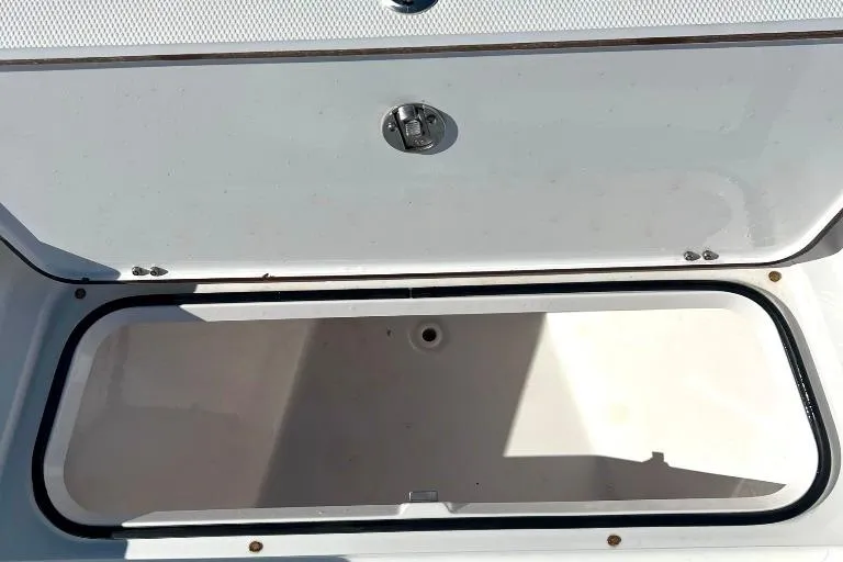 Slide: The Image of Open storage compartment on a 2015 BlackJack 224 boat, featuring a secure latch. - 27