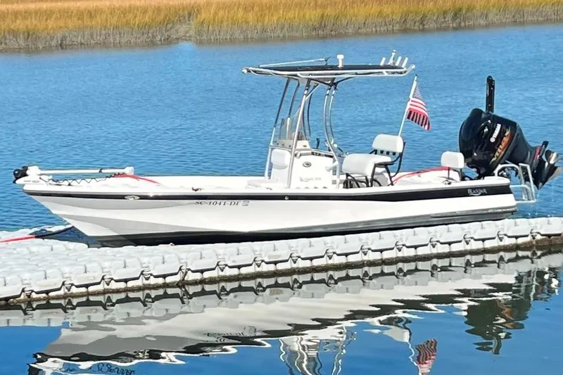 Slide: The Image of 2015 BlackJack 224 boat docked on calm water with American flag. - 6