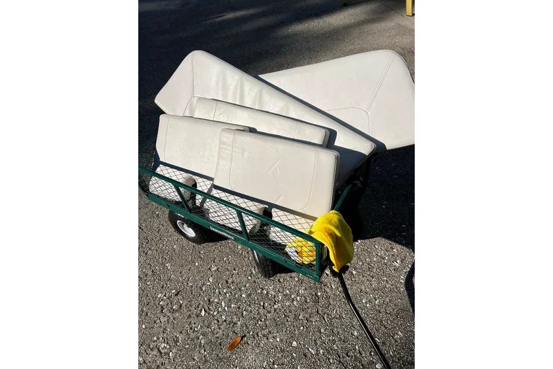Slide: The Image of A BlackJack 224 boat's white cushions on a green cart, outdoors, with a yellow cloth. - 9