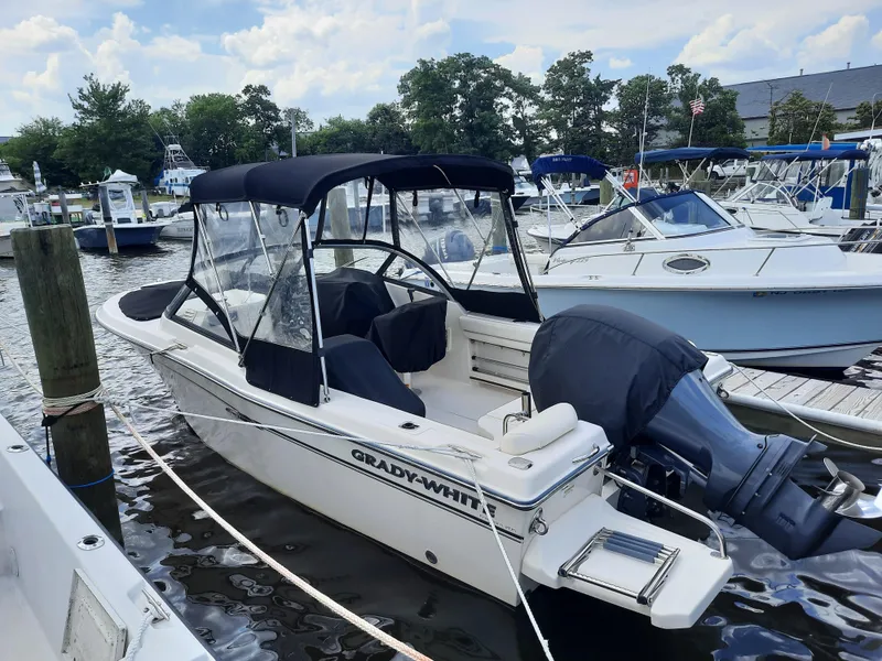 Slide: The Image of 2016 Grady-White Freedom 205 boat docked at marina, featuring black canopy and outboard motor. - 4