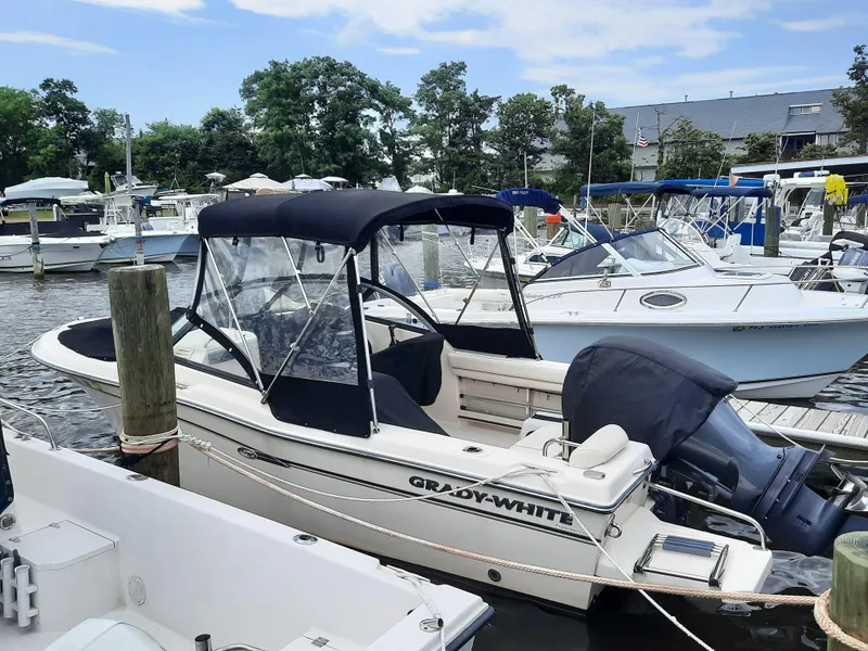 Slide: The Image of 2016 Grady-White Freedom 205 boat docked at marina, featuring black canopy and outboard motor. - 8