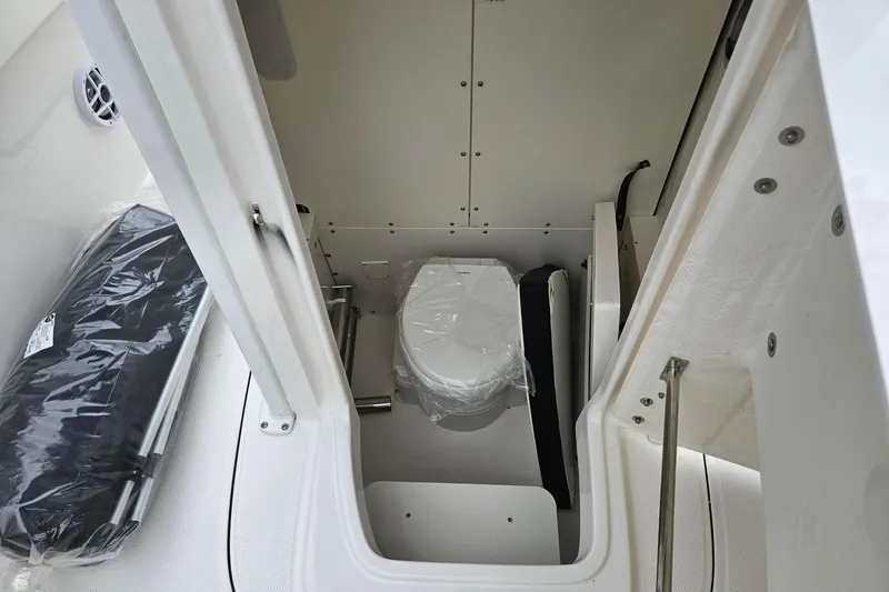 Slide: The Image of 2025 Robalo R230 Center Console boat interior with compact toilet and storage area. - 11
