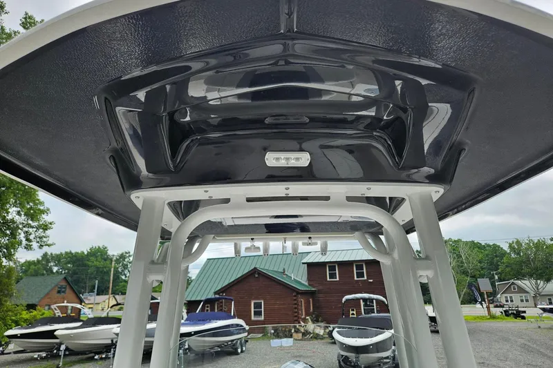 Slide: The Image of 2025 Robalo R230 Center Console boat with sleek T-top design, displayed outdoors. - 12