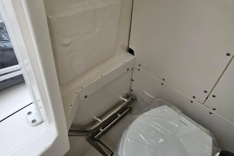 Slide: The Image of 2025 Robalo R230 Center Console boat interior with compact marine toilet. - 19