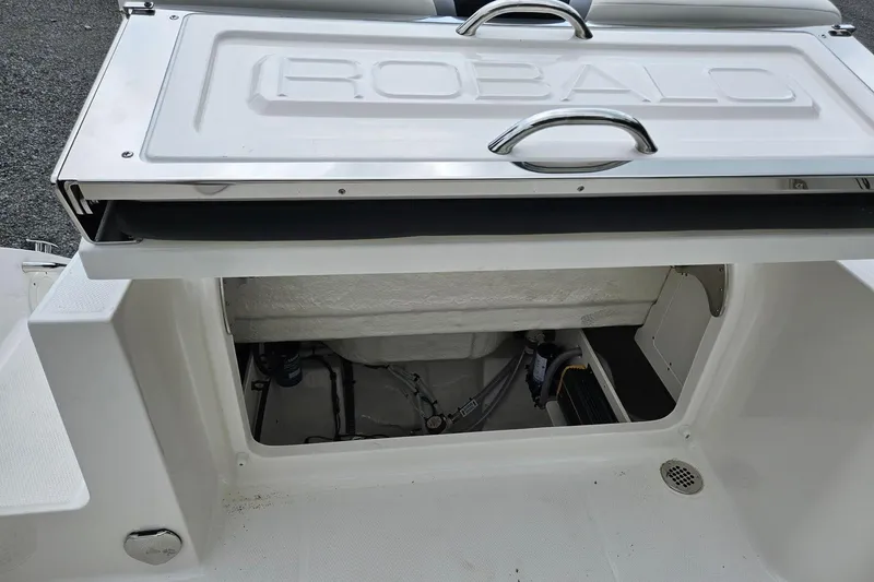 Slide: The Image of 2025 Robalo R230 Center Console storage compartment with open hatch, showcasing interior space. - 20