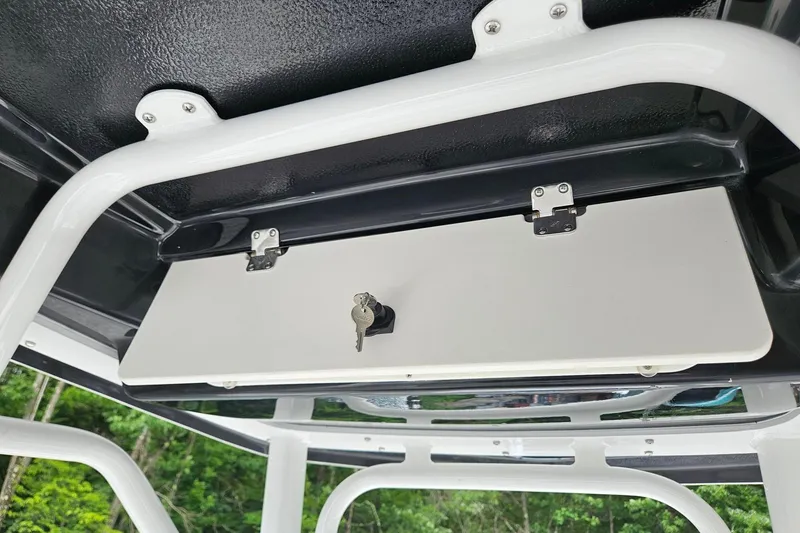 Slide: The Image of 2025 Robalo R230 Center Console storage compartment with key lock, featuring sturdy white frame. - 32