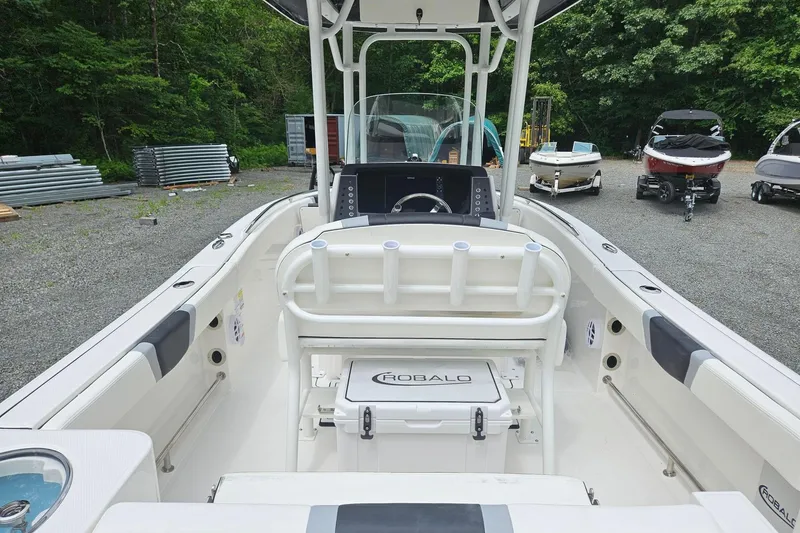 Slide: The Image of 2025 Robalo R230 Center Console boat interior with steering console and seating, parked outdoors. - 8
