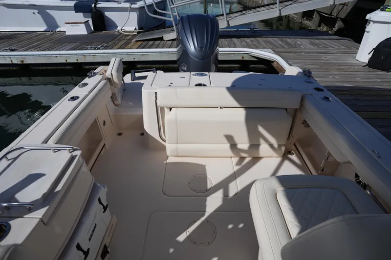 Slide: The Image of 2022 Grady-White Freedom 235 boat interior at dock, featuring seating and storage. - 14