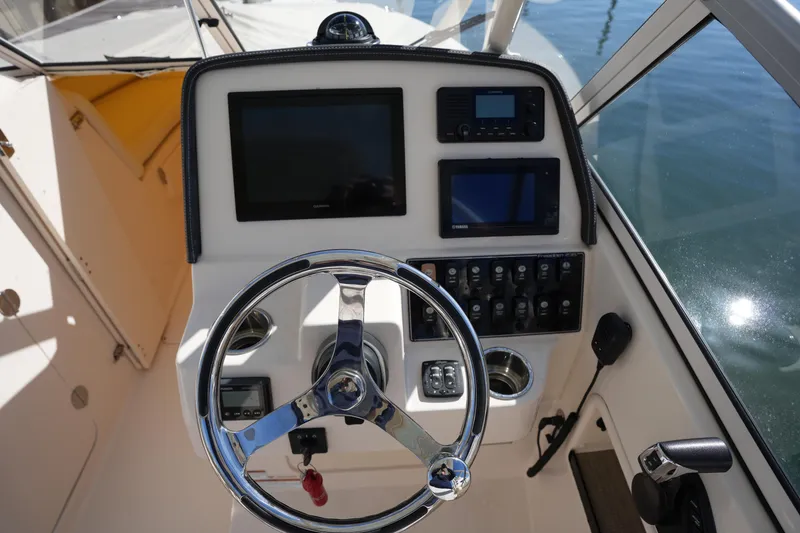 Slide: The Image of 2022 Grady-White Freedom 235 boat dashboard with steering wheel and electronic controls. - 23