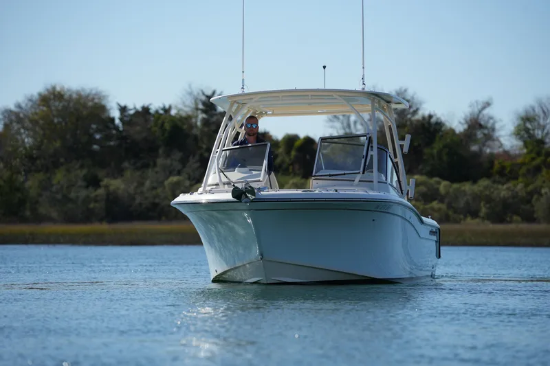 Slide: The Image of 2022 Grady-White Freedom 235 boat cruising on calm water, surrounded by lush greenery. - 3