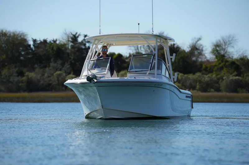 Slide: The Image of 2022 Grady-White Freedom 235 boat cruising on calm water, surrounded by trees. - 4