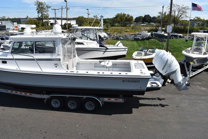 Slide: The Image of 2023 Steiger Craft 31 Miami boat on trailer, parked outdoors in a marina setting. - 5