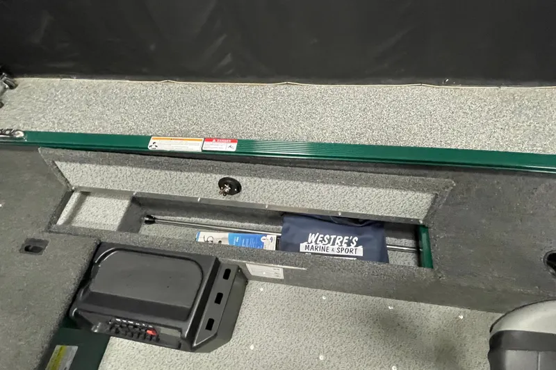 Slide: The Image of 2025 Lund 1650 Angler Tiller boat interior with storage compartment and marine equipment. - 14