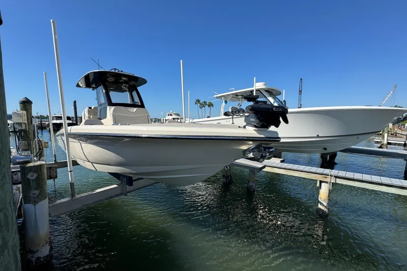 Slide: The Image of 2025 Scout 281 XSS boat docked at marina under clear blue sky. - 2