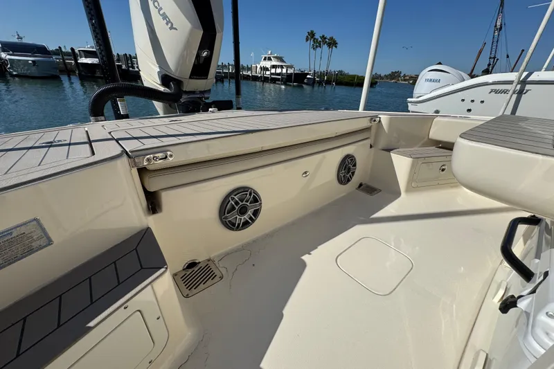 Slide: The Image of 2025 Scout 281 XSS boat interior with seating and storage, docked by the water. - 28