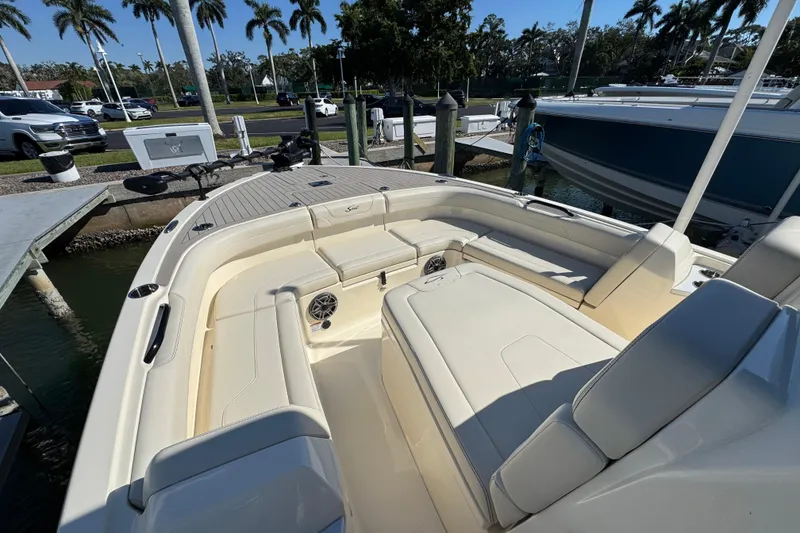 Slide: The Image of 2025 Scout 281 XSS boat interior with plush seating and modern design at a marina. - 8