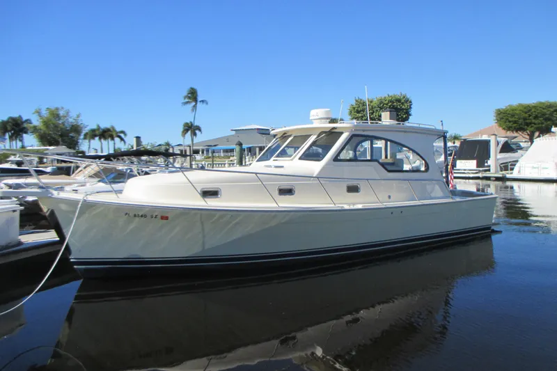 The Image of 2005 Mainship Pilot 34 Sedan boat docked in a marina under clear blue skies. - 0