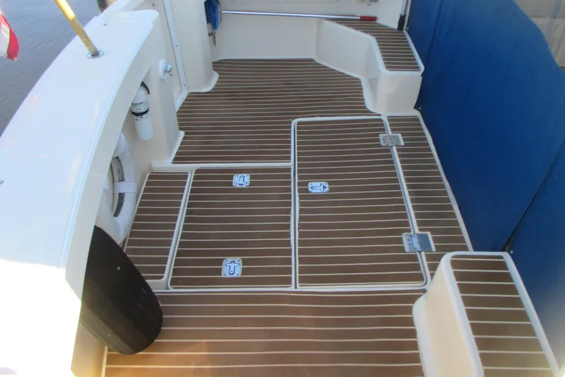 Slide: The Image of 2005 Mainship Pilot 34 Sedan boat deck with teak flooring and storage hatches. - 12