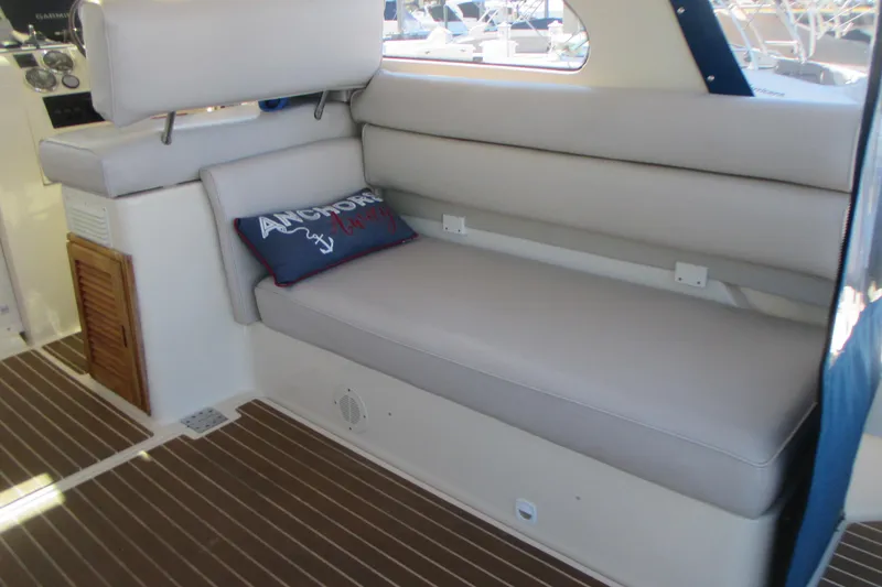 Slide: The Image of 2005 Mainship Pilot 34 Sedan interior with cushioned seating and nautical-themed pillow. - 16