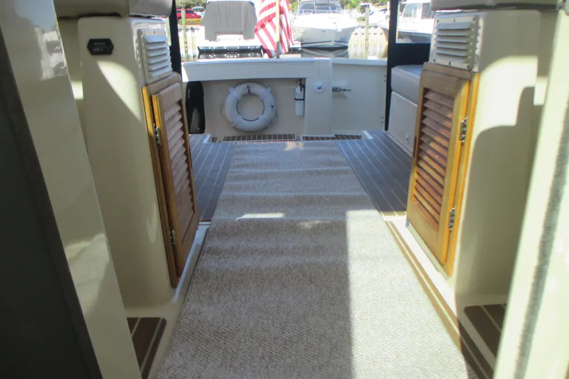 Slide: The Image of 2005 Mainship Pilot 34 Sedan interior with wooden cabinets and carpeted flooring. - 18