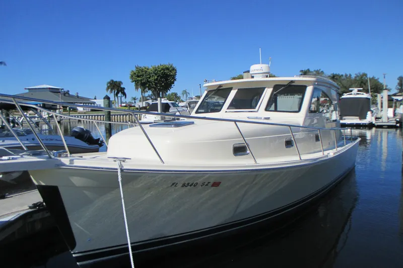 Slide: The Image of 2005 Mainship Pilot 34 Sedan docked in a marina under clear blue skies. - 2