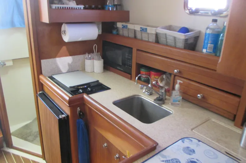 Slide: The Image of 2005 Mainship Pilot 34 Sedan galley with sink, stove, and storage cabinets. - 27