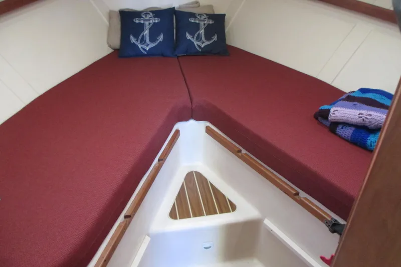 Slide: The Image of 2005 Mainship Pilot 34 Sedan cabin with red cushions and anchor-themed pillows. - 29