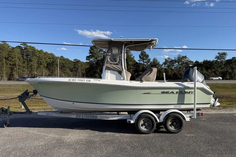 Slide: The Image of 2010 Sea Hunt Ultra 210 boat on trailer, parked roadside under clear sky. - 7