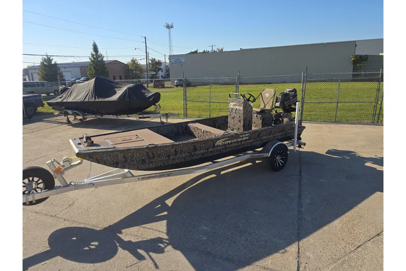Slide: The Image of 2026 Pro-Drive 1856 SBX TD boat on trailer, camo design, parked outdoors. - 6