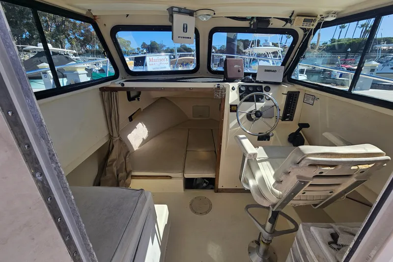 Slide: The Image of Interior of a 2000 Parker 2520 Sport Cabin boat with steering wheel and seating. - 10