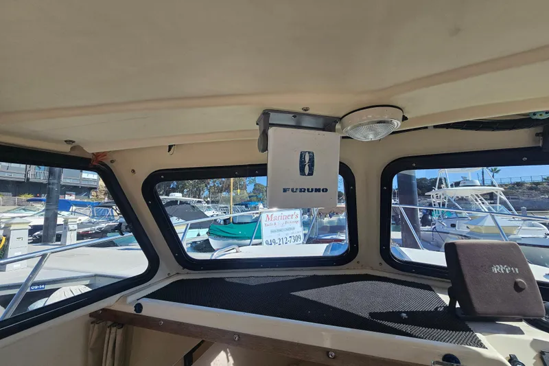 Slide: The Image of Interior view of a 2000 Parker 2520 Sport Cabin boat with marina background. - 11