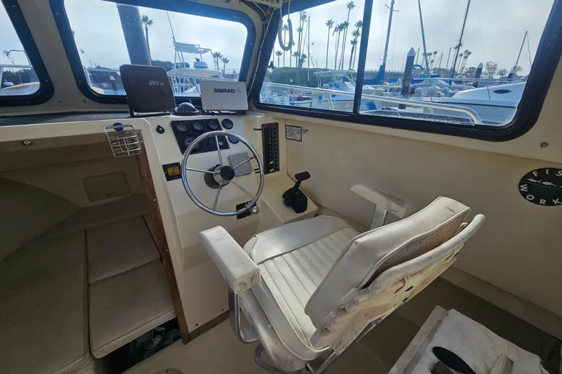 Slide: The Image of Interior of a 2000 Parker 2520 Sport Cabin boat with steering wheel and captain's chair. - 14