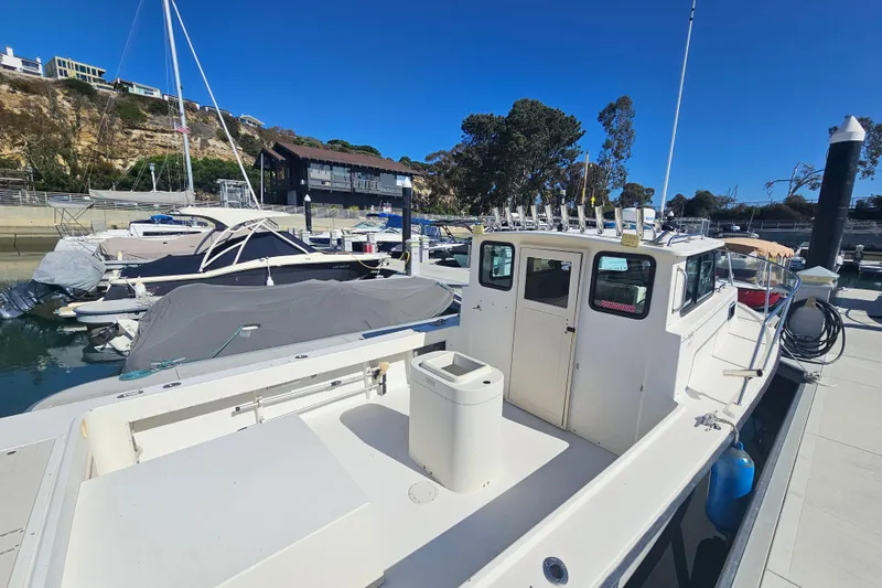 Slide: The Image of 2000 Parker 2520 Sport Cabin boat docked at marina under clear blue sky. - 2