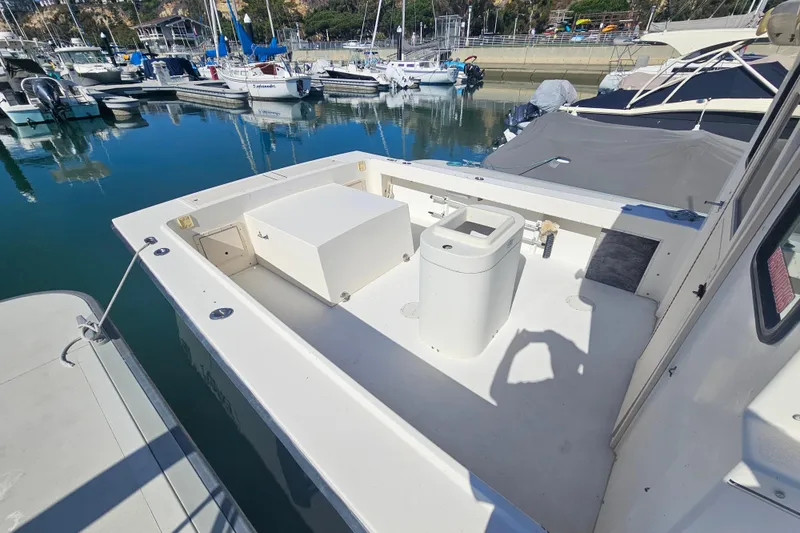 Slide: The Image of 2000 Parker 2520 Sport Cabin boat docked in a marina, showcasing spacious deck area. - 4