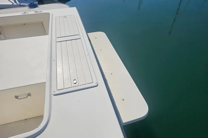 Slide: The Image of 2000 Parker 2520 Sport Cabin boat deck with storage compartment, docked on calm water. - 7