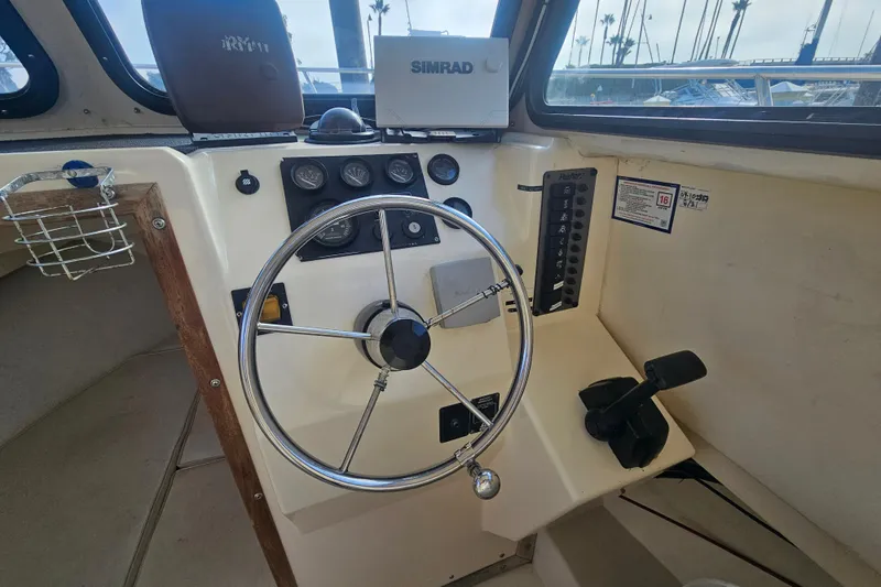 Slide: The Image of Steering wheel and controls of a 2000 Parker 2520 Sport Cabin boat. - 9