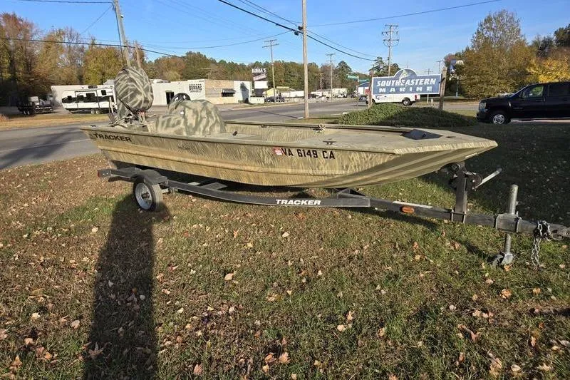The Image of 2017 Tracker Grizzly 1648 MVX Jon boat on trailer, parked outdoors near marine shop. - 0