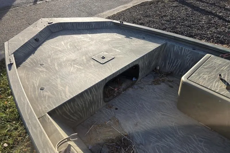 Slide: The Image of 2017 Tracker Grizzly 1648 MVX Jon boat interior with storage compartment and camouflage pattern. - 4