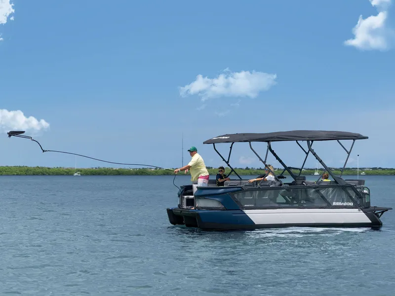 Slide: The Image of 2024 Sea-Doo Switch Cruise 21' 230 hp on water, person casting line, clear sky. - 13