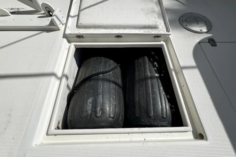 Slide: The Image of Open storage compartment on 2004 Dusky 33 boat deck with black fenders inside. - 11