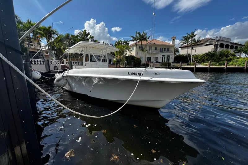 Slide: The Image of 2004 Dusky 33 boat docked by waterfront homes under a clear blue sky. - 2