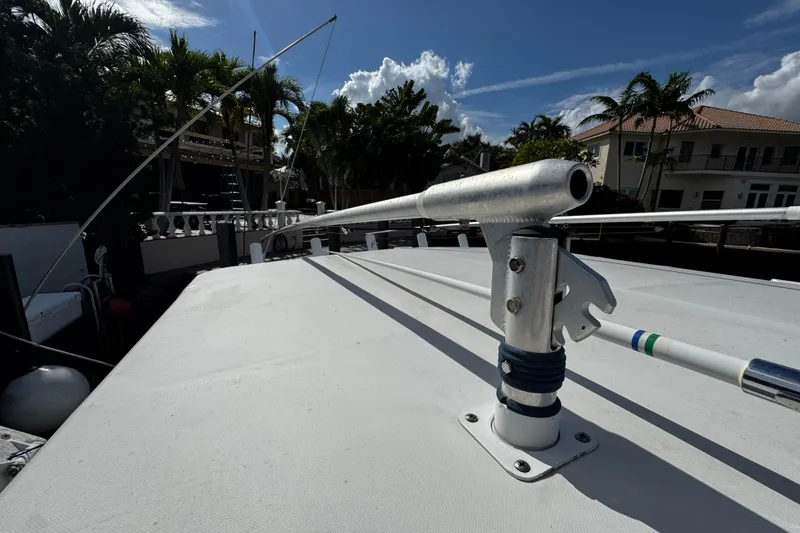 Slide: The Image of 2004 Dusky 33 boat deck with fishing rod holders, surrounded by palm trees and houses. - 39