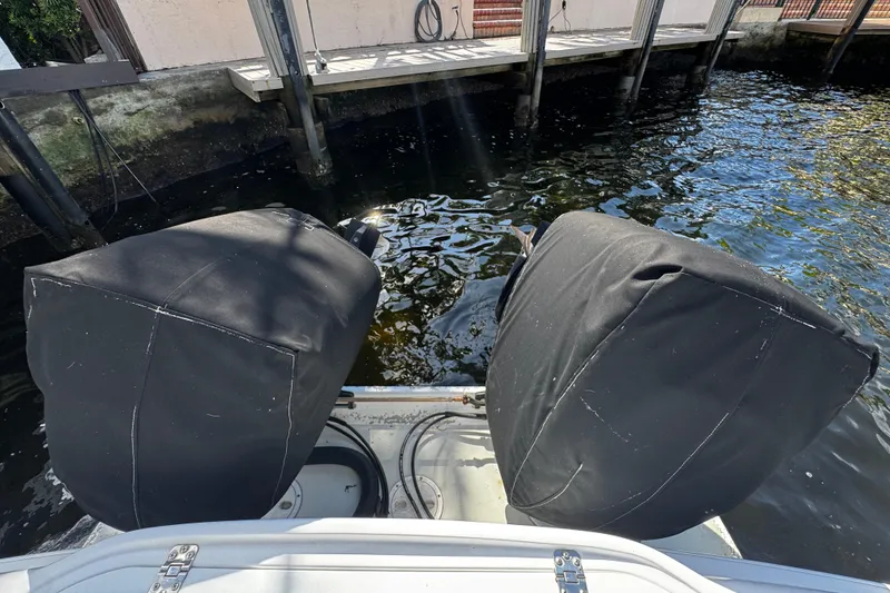 Slide: The Image of 2004 Dusky 33 boat with covered outboard motors docked by the water. - 44