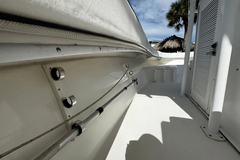 Slide: The Image of 2004 Dusky 33 boat deck with rod holders and storage, under clear sky. - 48